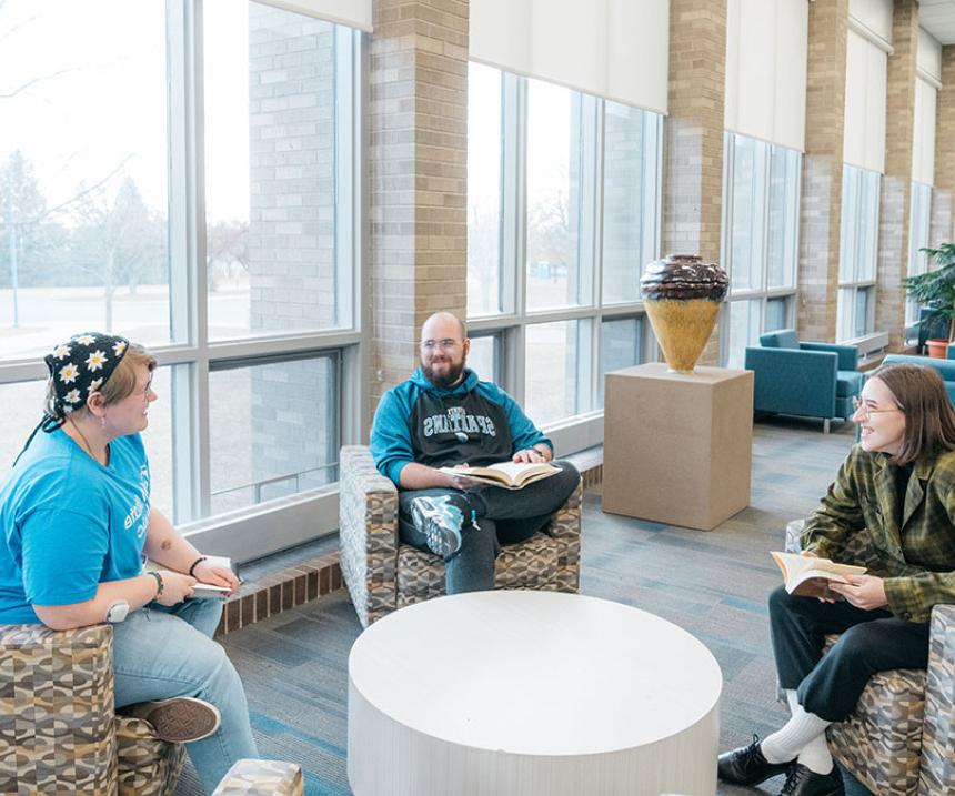 Three people sit in a lounge talking